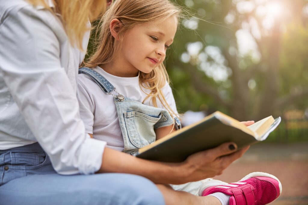 Little girl spending time at the book with nanny