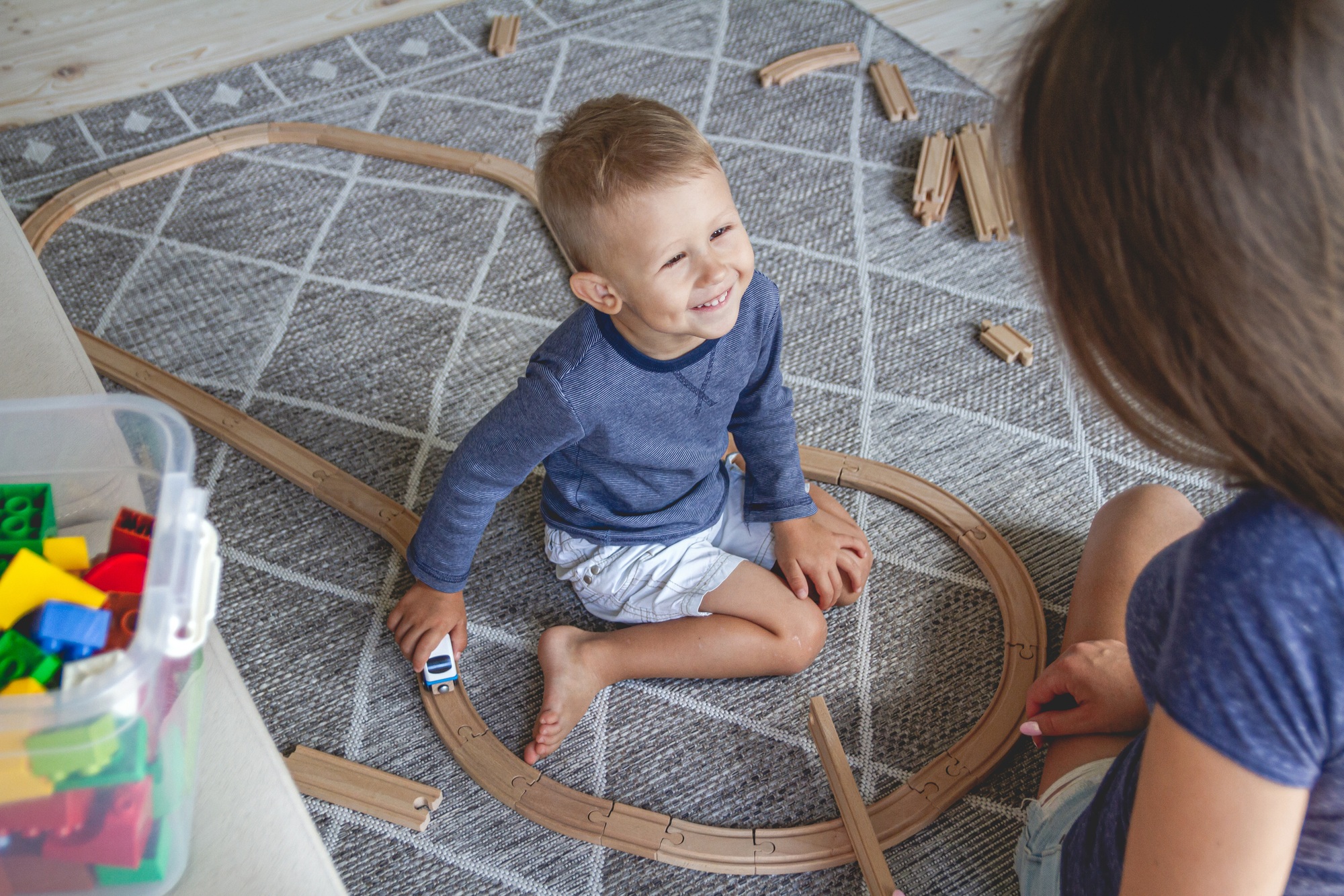 Little kid boy and his mother playing with railway