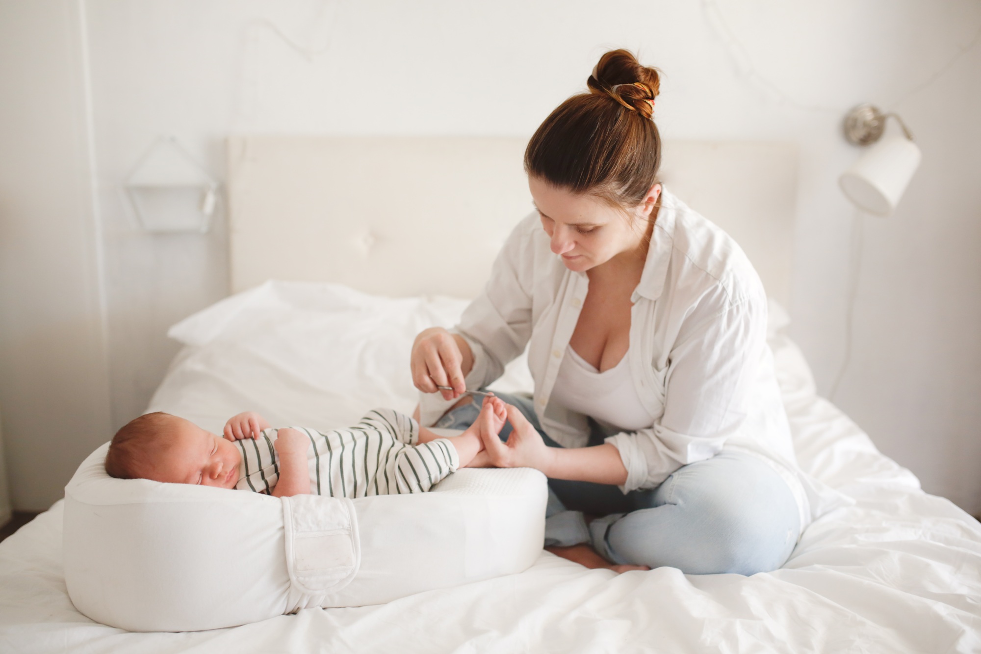 motherhood and childcare, mom gently holds the baby's toes and cuts the nails
